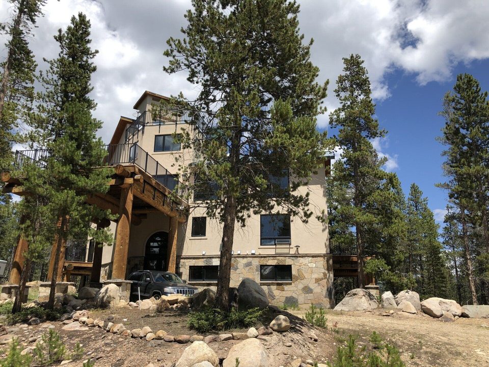 A four-story mountain lodge with log posts and iron-railed decks among lodgepole pines